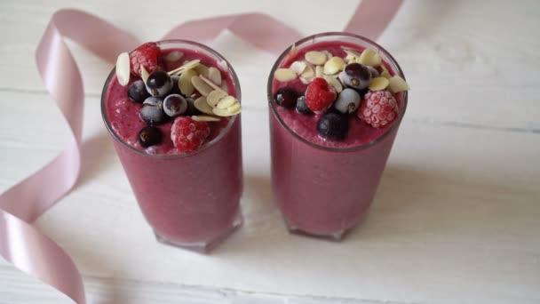 Δύο ποτήρια smoothie, milkshake ροζ φρούτα smoothies ή κοκτέιλ σε λευκό φόντο ξύλινη. Υγιή ζουμερά βιταμίνη ποτό δίαιτα ή vegan ωμά τρόφιμα έννοια — Αρχείο Βίντεο