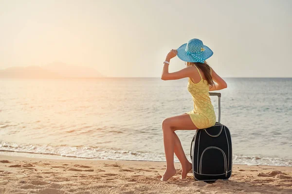 美丽的年轻妇女站在与手提箱在美妙的海背景, 时间的概念旅行 — 图库照片