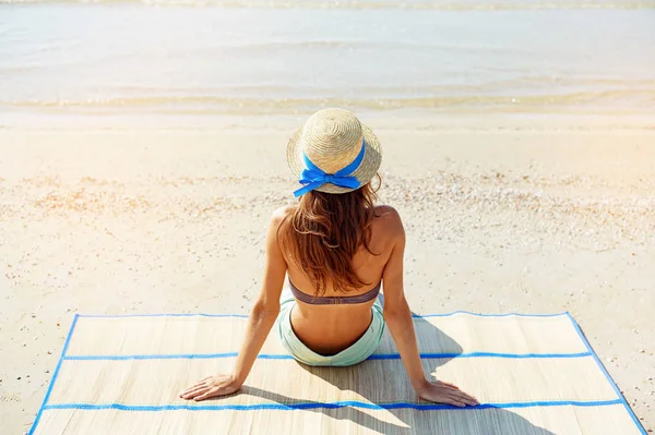 Sommer-Lifestyle-Porträt einer hübschen jungen, sonnengebräunten Frau mit Hut. Das Leben genießen und am Strand sitzen, Zeit zum Reisen. Blick auf das Meer — Stockfoto