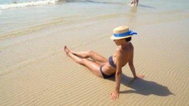 Yaz yaşam tarzı Hd video bronzlaşmış kadında genç ve güzel bir şapka. Hayattan zevk ve sahilde oturup, seyahat zamanı. Denize bakarak