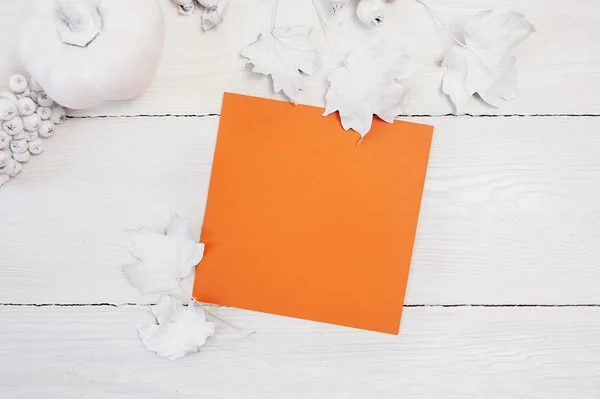 Twee oranje vellen papier, de witte pompoen, de bessen en de bladeren op een houten achtergrond. mockup herfst. Wenskaart voor Thanksgiving Day in rustieke stijl met ruimte voor uw tekst. Flat lag. Bovenaanzicht — Stockfoto