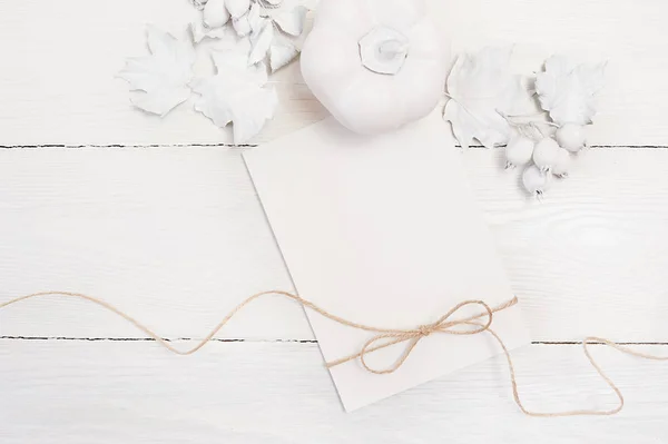 Corda di lino, zucca bianca, bacche e foglie, modellano un foglio bianco autunnale su uno sfondo di legno. Biglietto di auguri per il Giorno del Ringraziamento in stile rustico con spazio per il testo. Piatto. Inizio pagina — Foto Stock