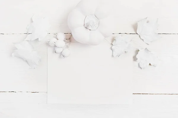 Mockup foglio bianco di carta con zucca, bacche e foglie su uno sfondo autunnale in legno. Biglietto di auguri per il Giorno del Ringraziamento in stile rustico con spazio per il testo. Piatto. Vista dall'alto — Foto Stock