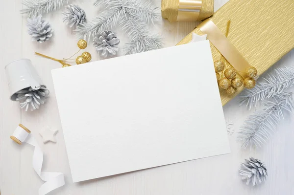 Abstrakta jul bakgrund, vita pappersark som ligger bland små dekorationer på vit trä skrivbord. Lägenheten låg mockup för din konst, bild eller hand bokstäver sammansättning kopia utrymme, ovanifrån — Stockfoto