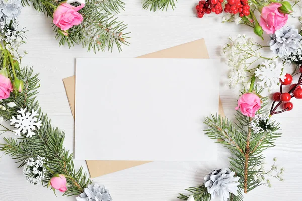 Weihnachtskranz-Attrappe in Herzform mit einem Blatt Papier, das mit weißen Schneeflocken und Zapfen verziert ist. weißer Holzhintergrund mit Platz für Ihren Text — Stockfoto