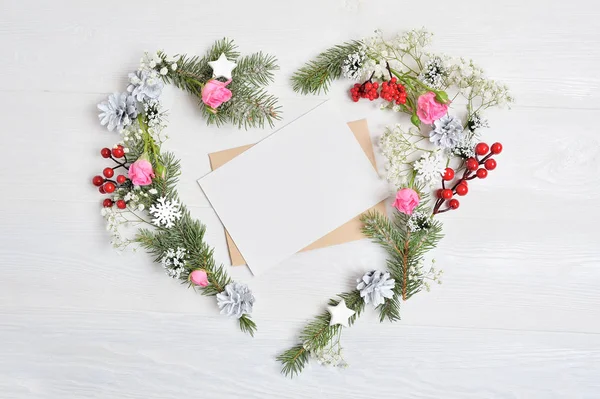 Κοροϊδεύω Χριστουγεννιάτικο στεφάνι με μορφή της καρδιάς με φύλλο χαρτί διακοσμημένο με λευκά νιφάδες χιονιού και κώνοι. Λευκό φόντο ξύλινο με θέση για το κείμενό σας — Φωτογραφία Αρχείου