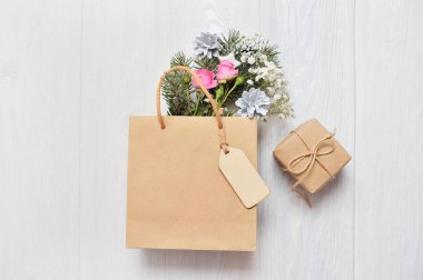 Noel mockup alışveriş kavramı. Ahşap etiket ve xmas dekor çam dalları, pembe gül, metniniz için yer ile koni ile Kraft paket