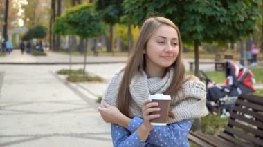 Yakın çekim sıcak çay veya kahve sonbahar parkta içen kadın yüz, o örme eşarp takıyor. kız içecekler kahve kupa gelen iyi bir ruh hali için.