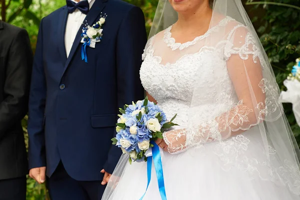 Hermoso ramo de rosas y hortensias en el fondo novia y novio stand en una ceremonia de boda —  Fotos de Stock