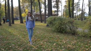Güzel ve genç birbayan örme eşarp ve sonbahar Park'ta yürüyordunuz giyer. 4 k video hareket