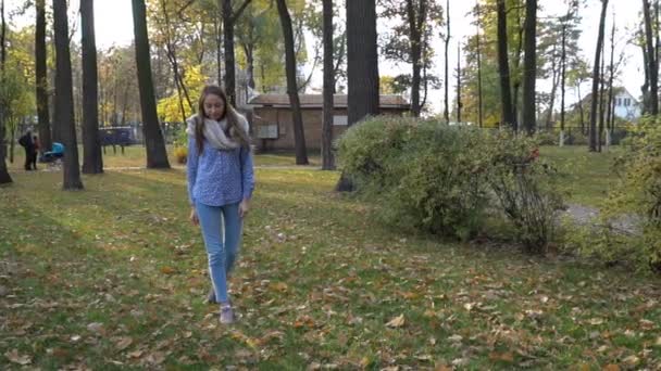 Hermosa mujer joven lleva bufanda de punto y caminar en el parque de otoño. Movimiento de vídeo 4k — Vídeos de Stock