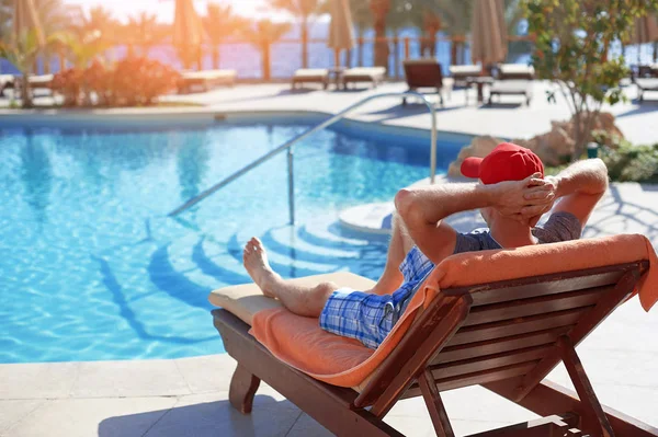 Pozytywny człowiek w czerwonym kapeluszu odpoczynku w pobliżu hotelu basen w Egipcie. Pojęcie piękna życia — Zdjęcie stockowe