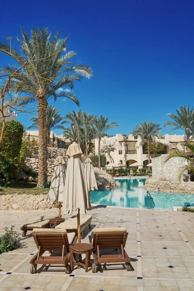 Sharm El Sheikh, Egipto - 9 de febrero de 2019: El Grand Hotel de cinco estrellas con palmeras y tumbonas cerca de la piscina en el territorio de verano —  Fotos de Stock