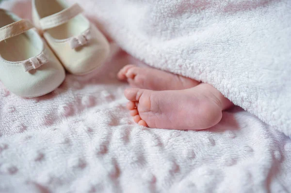 Los pies desnudos de un bebé recién nacido lindo en manta blanca cálida. Infancia. Pequeños pies desnudos de una niña. Niño recién nacido dormido —  Fotos de Stock