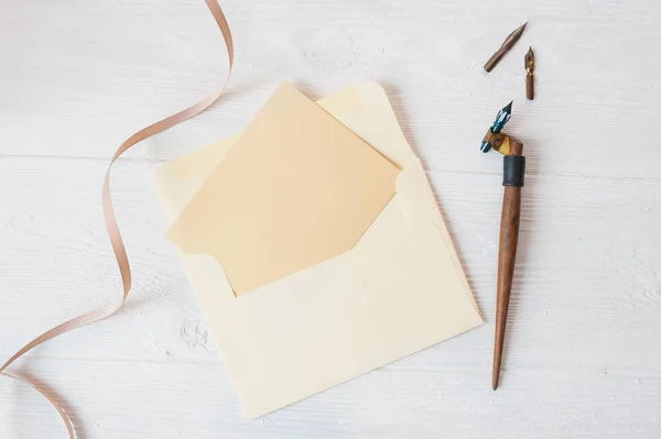 Mockup carta de vacaciones Papel en blanco y un sobre con pluma en la mesa de madera, con espacio para su texto, vista superior —  Fotos de Stock