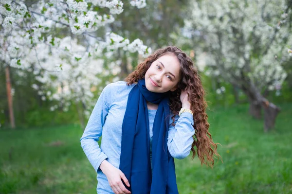 Retrato de uma jovem bela mulher na moda no parque florescente de primavera. Menina feliz posando em um jardim florescente com flores brancas — Fotografia de Stock