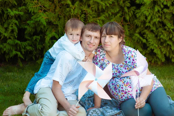 Happy family in the park. Happy Mom, dad and baby sits on grass. The concept of a happy family. Father hold boy — Stock Photo, Image