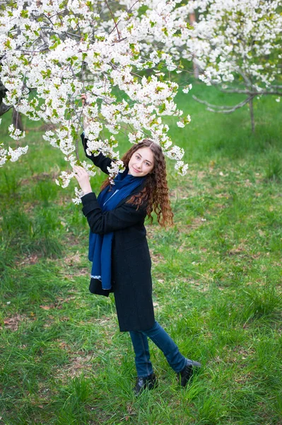 Retrato de uma jovem bela mulher na moda no parque florescente de primavera. Menina feliz posando em um jardim florescente com flores brancas — Fotografia de Stock