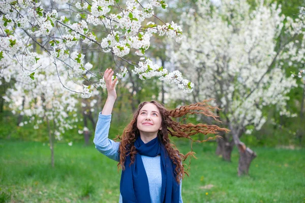 Porträt einer jungen schönen modischen Frau im frühlingshaft blühenden Park. glückliches Mädchen posiert in einem blühenden Garten mit weißen Blumen — Stockfoto