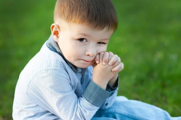 Leuke jongen zit op groen gras. Hij wacht. Concept van Childrens Happy — Stockfoto