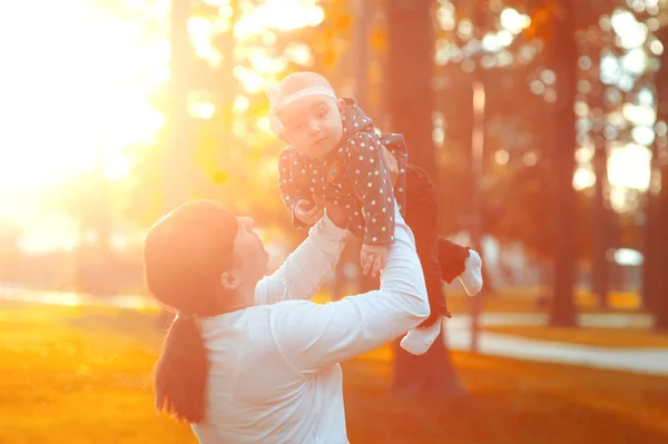 Mamá juega con su pequeña hija, joven mujer feliz y linda disfrutando y jugando con su hija niña sosteniéndola levantándose en sus brazos —  Fotos de Stock