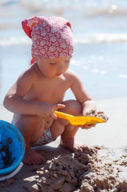 Çocuk kız sahilde oynuyor. Plajda çocuk inşa kum kale. Aile için yaz suyu eğlencesi. Deniz kıyısında oyuncak kovalar ve Spade ile kız