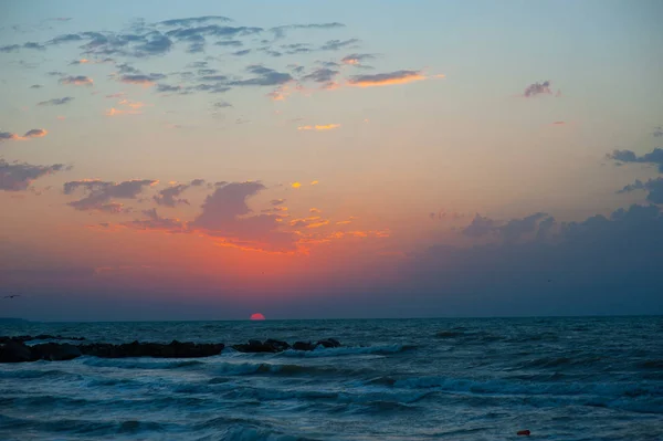 Incroyable coucher de soleil sur la plage avec un horizon sans fin au loin, et d'incroyables vagues mousseuses. Nuages rouges sur le fond — Photo