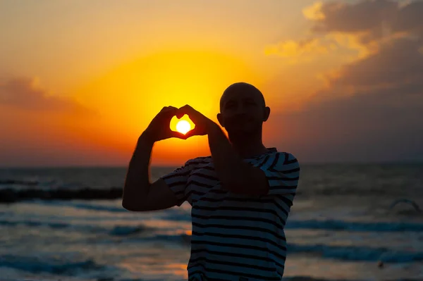 Male hands in the form of heart against the sky pass sun beams. Hands in shape of love heart — Stock Photo, Image