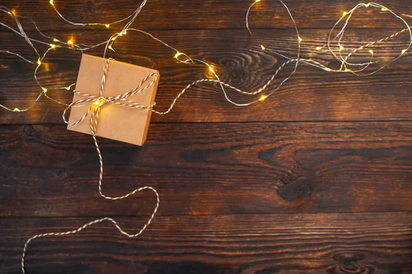 Mockup Christmas kraft gift box with xmas garland on wooden background. Top view for greeting card with place for text — Stock Photo, Image