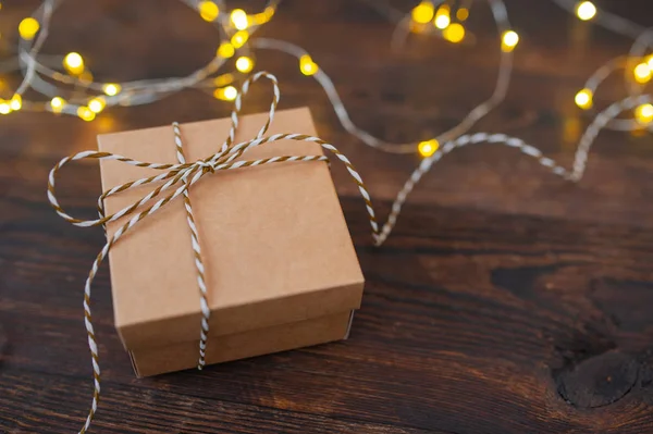 Макет рождественский крафт подарочная коробка с гирляндой Xmas на деревянном фоне. Вид сверху на поздравительную открытку с местом для текста — стоковое фото