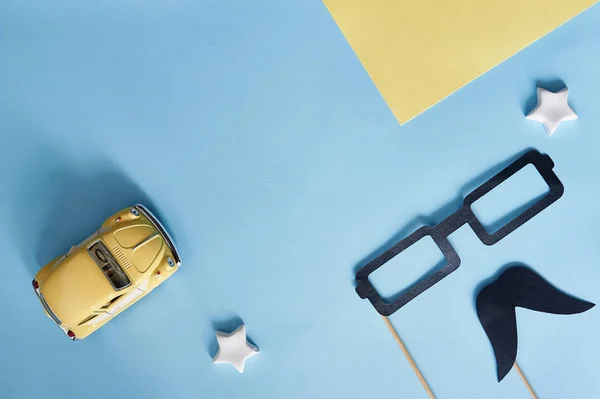 基夫,乌克兰 - 2019年6月6日:父亲节快乐顶视图。装饰黑色纸胡子,眼镜和黄色玩具车在蓝色背景与文本的地方 — 图库照片