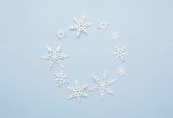 Corona di composizione natalizia o invernale. Cornice di fiocchi di neve bianchi su sfondo blu pastello. Natale, inverno, capodanno. Layout piatto, vista dall'alto, spazio di copia — Foto Stock