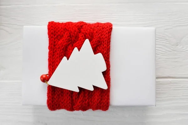 Biały Boże Narodzenie pudełko z czerwonym dzianiny wstążki i tag makieta w formie jodły na białym tle. Zamknij widok z góry — Zdjęcie stockowe