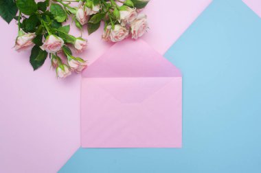 Mockup boş pembe zarf ve pembe gül tomurcukları, şenlikli arka plan, kopya alanı