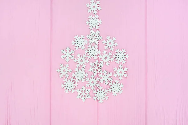 Boule de Noël stylisée faite de flocons de neige en bois blanc sur fond en bois rose avec place pour le texte. Concept pour carte de vœux de Noël, jour férié du Nouvel An — Photo