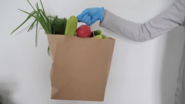 Kadınlar göğüs göğüse koruyucu eldivenler takıyor. Sebze dolu, kağıt poşet servis ediliyor. Güvenli karantina, ulaşılamayan teslimat servisi yiyeceği. Paketleme şablonu. Boşluğu kopyala