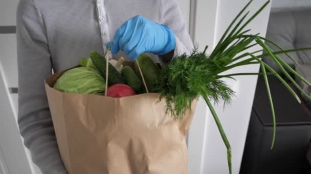 Bénévole dans les gants bleus détient des légumes paquet de don alimentaire pour aider les autres. paquet de dons avec des aliments. Vidéo en Full HD — Video