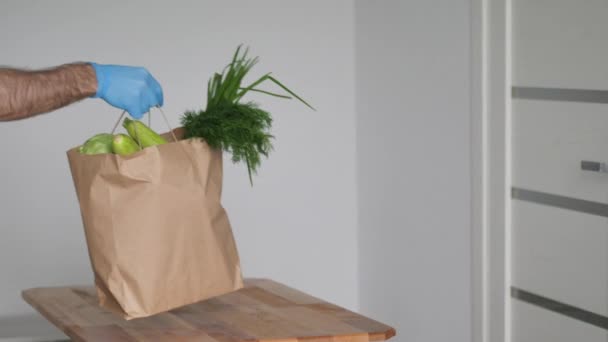 Les prises homme donnent de main en main dans des gants de protection plein légumes sac en papier à emporter. Mise en quarantaine des aliments sans contact de service de livraison. Modèle d'emballage. Espace de copie — Video