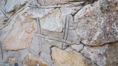 Dikişleri olan eski taşların dokusu. Sefil duvarcılığa yakın çekim. Değişik antik kaldırım taşlarından yapılmış taş duvar..