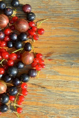 Ahşap arka plan üzerinde kırmızı ve siyah frenk üzümü. Yaz berry