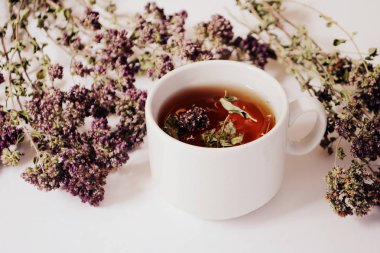 Bardak bitkisel çay ve hafif bir arka plan üzerinde otlar.