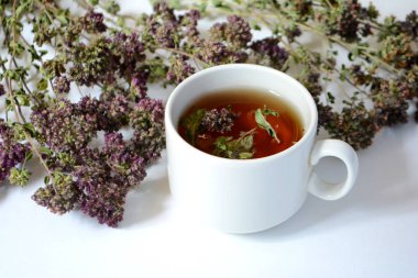 Bardak bitkisel çay ve hafif bir arka plan üzerinde otlar.