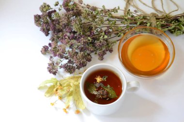 Bardak bitkisel çay, bal, hafif bir arka plan üzerinde otlar. Kopya alanı