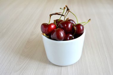 Kiraz ahşap arka plan üzerinde beyaz Kupası