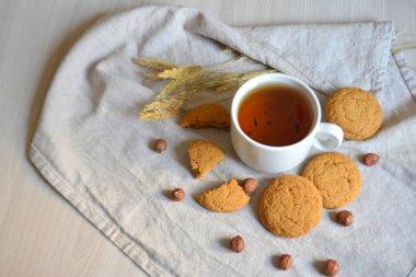 Çay bir fincan, yulaf ezmeli kurabiye ve masanın üzerine fındık