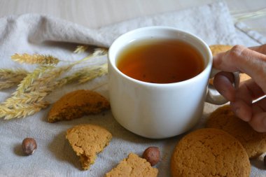 El, yulaf ezmeli kurabiye ve fındık masada bir fincan çay