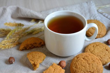 Çay bir fincan, yulaf ezmeli kurabiye ve masanın üzerine fındık