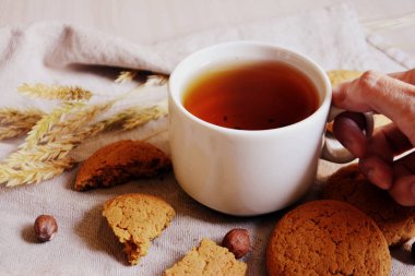 El, yulaf ezmeli kurabiye ve fındık masada bir fincan çay