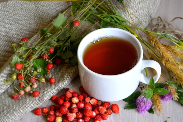 Tasse Tee Blumen Und Walderdbeeren Auf Dem Tisch — Stockfoto