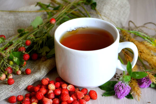 Tasse Tee Blumen Und Walderdbeeren Auf Dem Tisch — Stockfoto